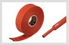A coil of flattened red anti-tracking heat shrink tube beside a short cut length of the same red tube